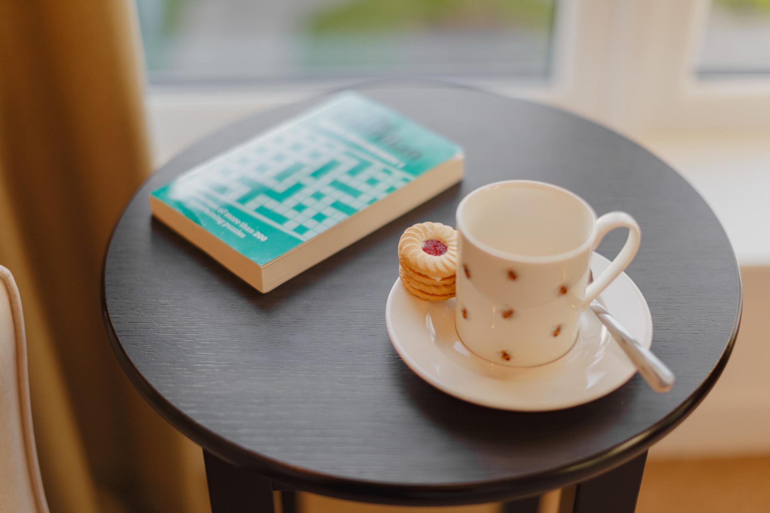 cut of tea with a biscuit and crossword book