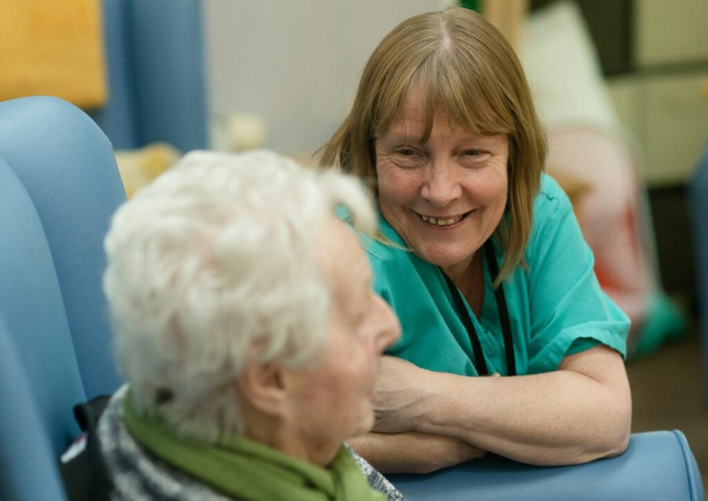 care home staff member in uniform smiling with a resident