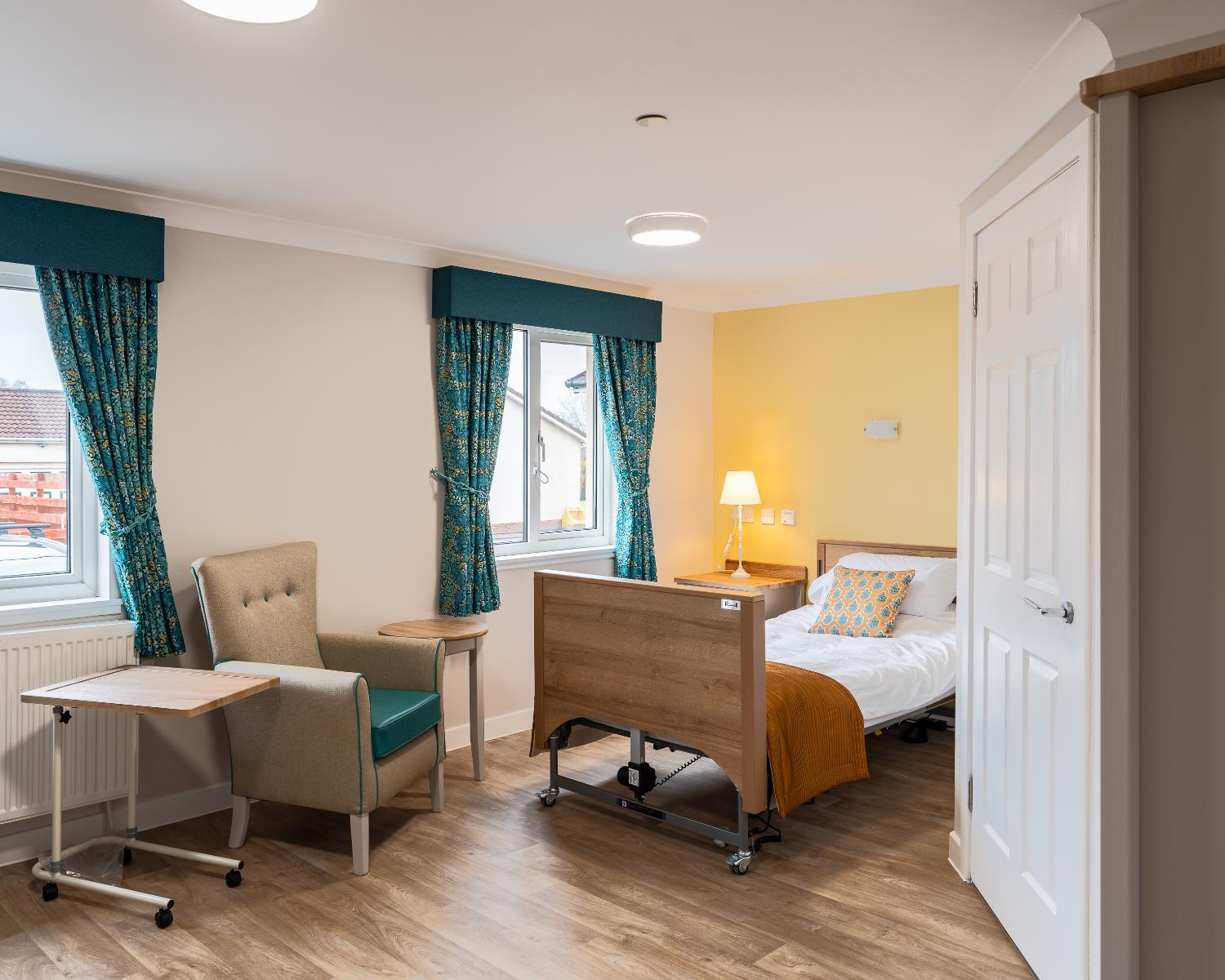 bedroom in ashlea court care home with profiling bed and armchair